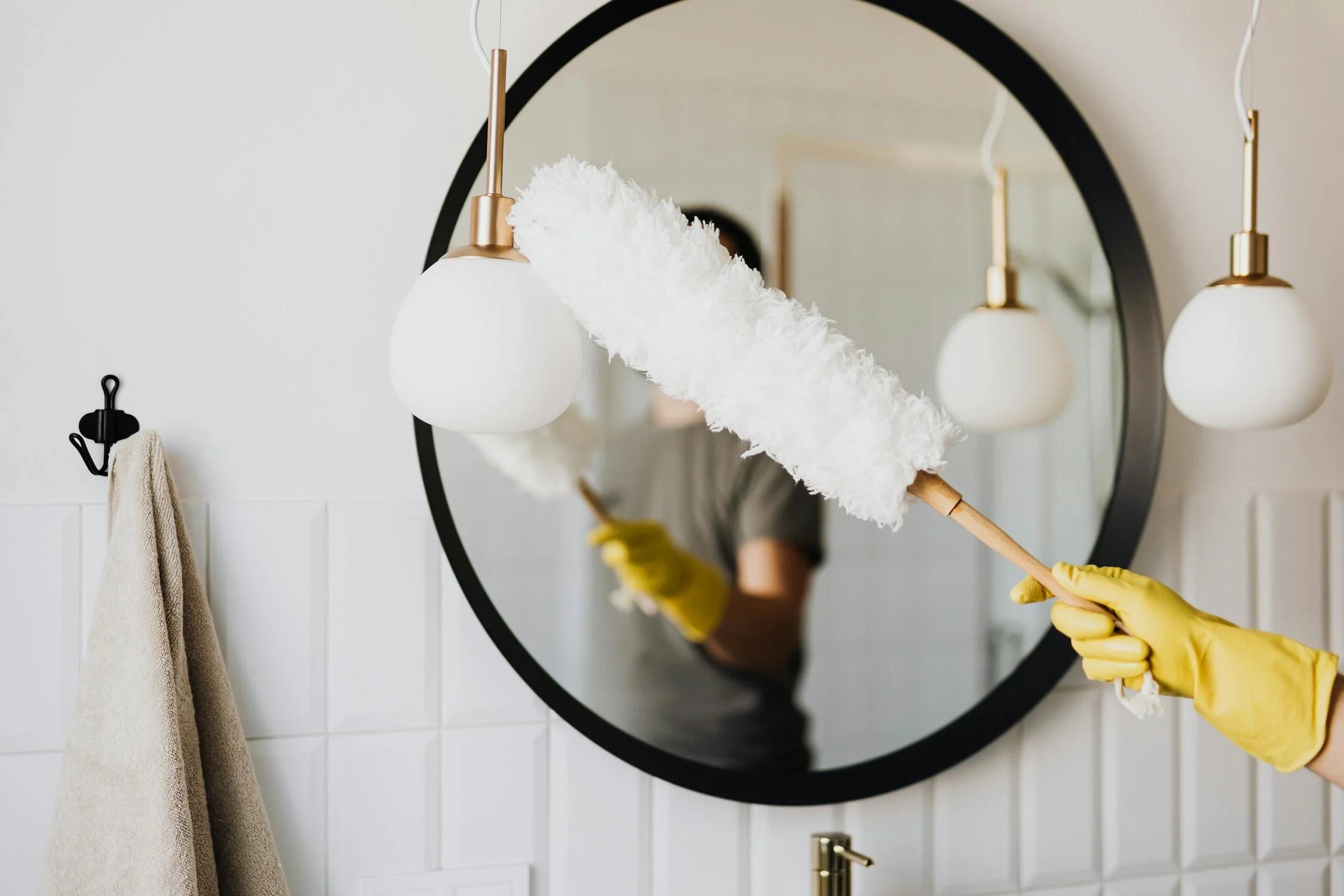 A House Cleaner Dusting A Light Fixture in a Bathroom