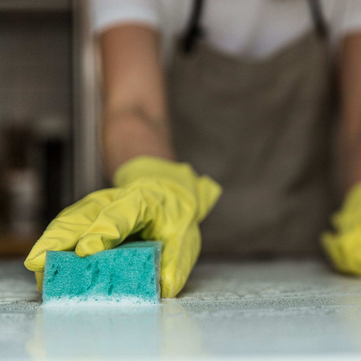 a cleaner with a yellow glove scrubbing countertop